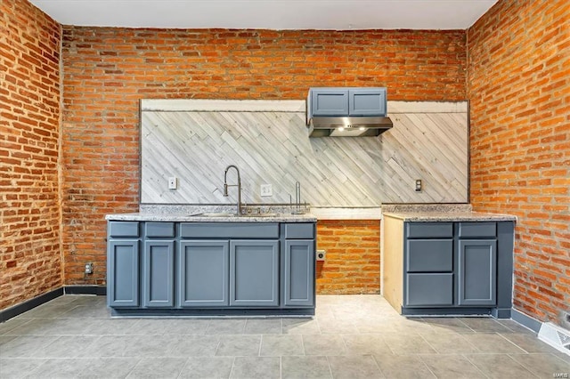 kitchen featuring brick wall and sink