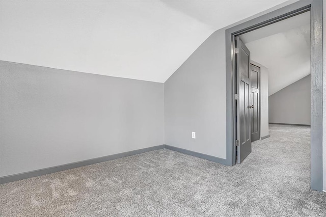 additional living space featuring vaulted ceiling and light carpet