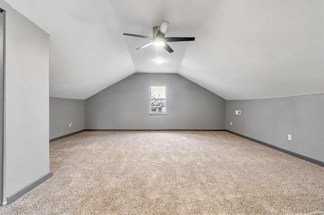 additional living space with ceiling fan, light colored carpet, and vaulted ceiling