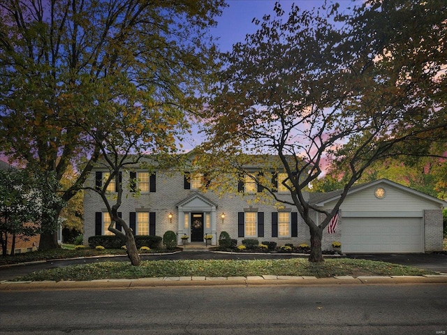 colonial-style house with brick siding, driveway, and a garage