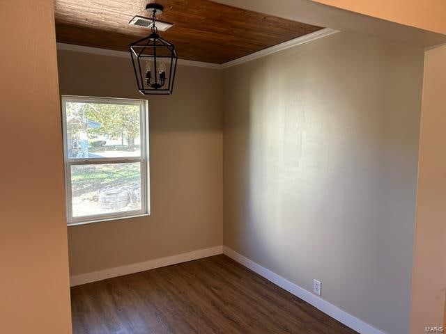 empty room featuring ornamental molding, dark wood-type flooring, wood ceiling, and a chandelier