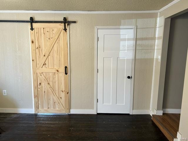 interior space with dark wood-type flooring, crown molding, a textured ceiling, and a barn door