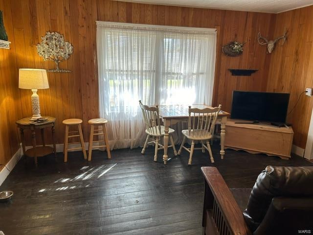 dining space with wooden walls and dark wood-type flooring