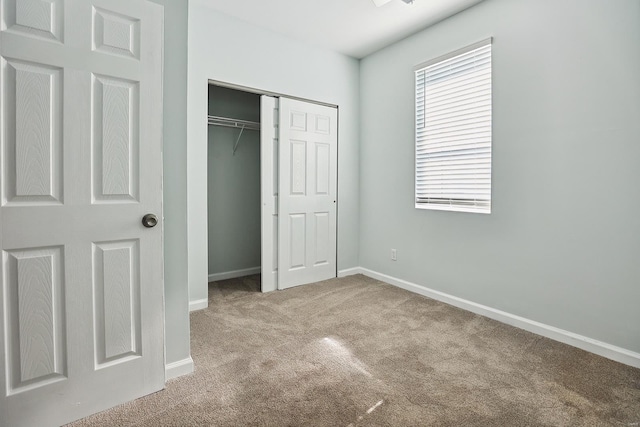 unfurnished bedroom featuring light carpet and a closet