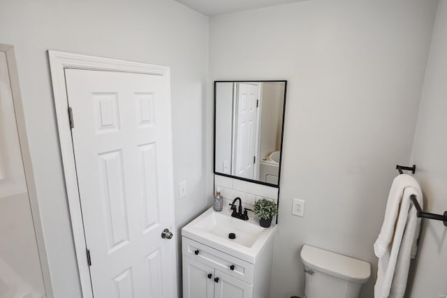 bathroom featuring vanity, toilet, and backsplash