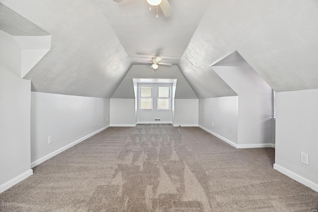 bonus room with lofted ceiling, ceiling fan, carpet, and a textured ceiling