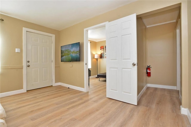 entryway with crown molding and light hardwood / wood-style floors