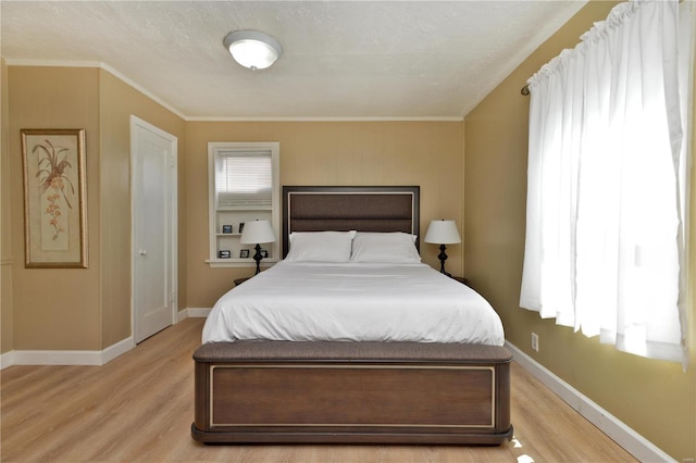 bedroom featuring light hardwood / wood-style floors, crown molding, and a textured ceiling