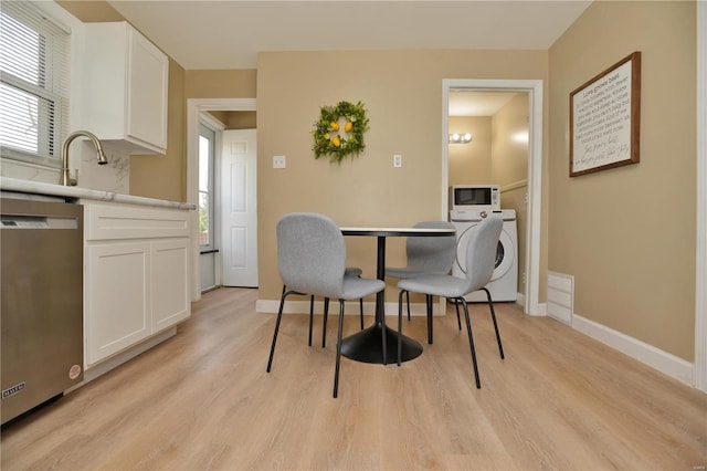 dining area with sink, light hardwood / wood-style floors, and washer / dryer