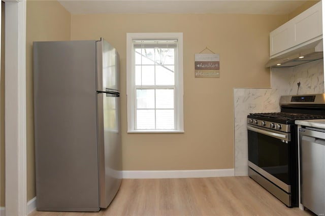 kitchen with ventilation hood, light hardwood / wood-style flooring, backsplash, appliances with stainless steel finishes, and white cabinetry