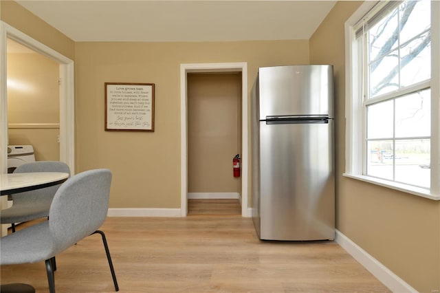 home office with light hardwood / wood-style floors and washer / dryer