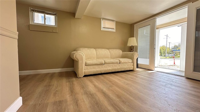 sitting room featuring light hardwood / wood-style floors, beamed ceiling, and a healthy amount of sunlight