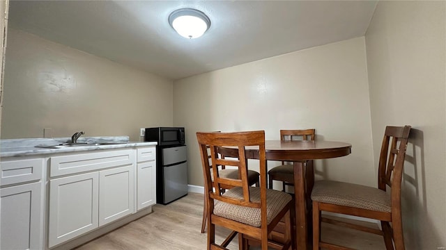 dining space featuring light wood-type flooring and sink