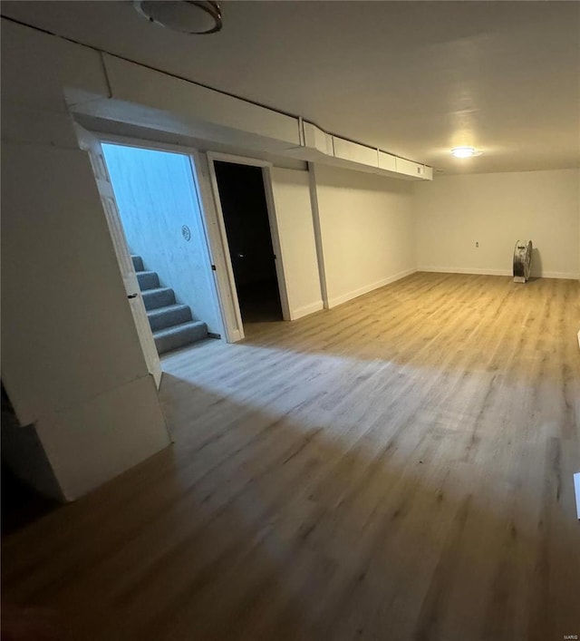 finished below grade area with baseboards, wood finished floors, and stairway