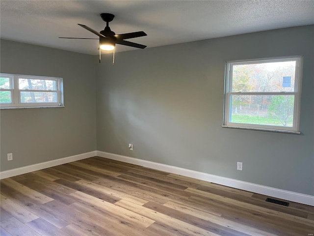 unfurnished room with a wealth of natural light, ceiling fan, a textured ceiling, and light wood-type flooring