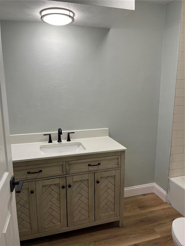 bathroom with toilet, vanity, wood-type flooring, and a textured ceiling