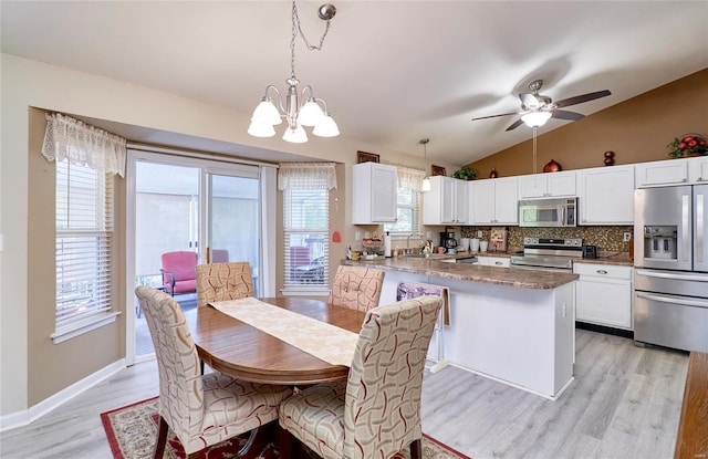 dining room with sink, light hardwood / wood-style floors, lofted ceiling, and ceiling fan with notable chandelier