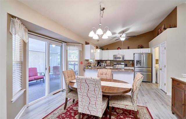 dining area with vaulted ceiling, ceiling fan with notable chandelier, and light wood-type flooring