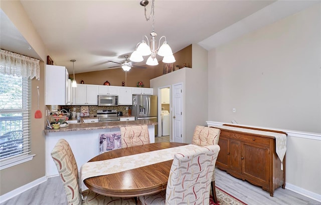 dining area with lofted ceiling, light wood-type flooring, and ceiling fan with notable chandelier