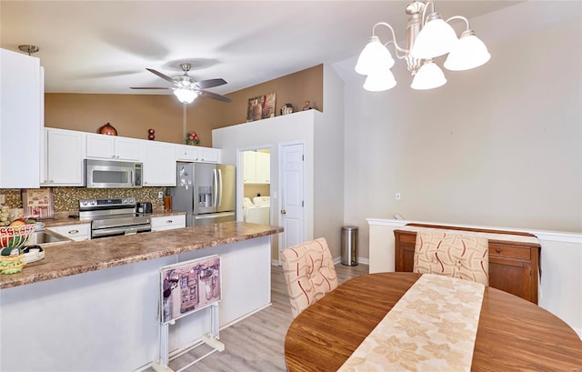 kitchen with vaulted ceiling, pendant lighting, white cabinetry, appliances with stainless steel finishes, and ceiling fan with notable chandelier