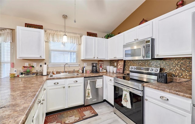 kitchen featuring appliances with stainless steel finishes, white cabinets, a healthy amount of sunlight, and sink