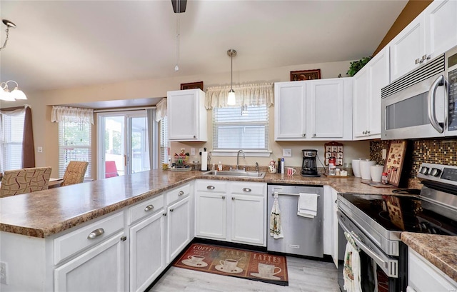 kitchen with appliances with stainless steel finishes, sink, light wood-type flooring, white cabinetry, and pendant lighting