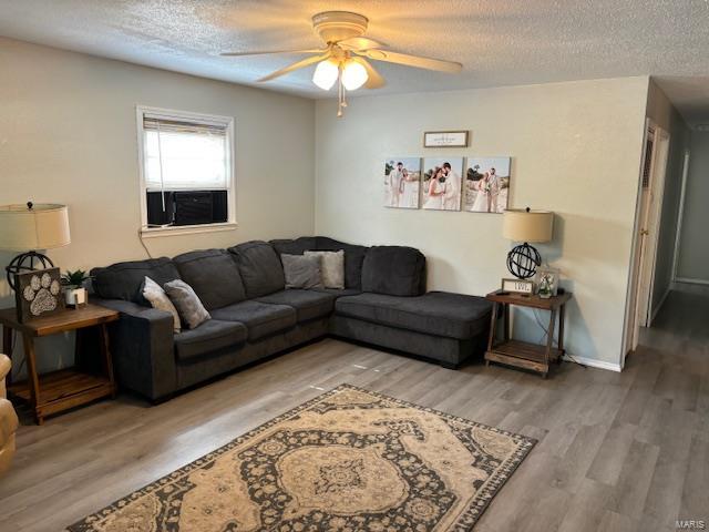 living room with ceiling fan, wood-type flooring, and a textured ceiling