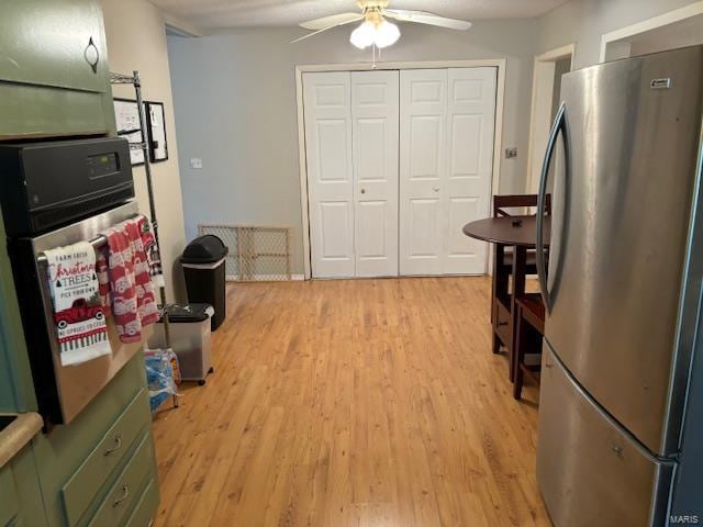 kitchen featuring ceiling fan, stainless steel fridge, green cabinets, and light hardwood / wood-style flooring