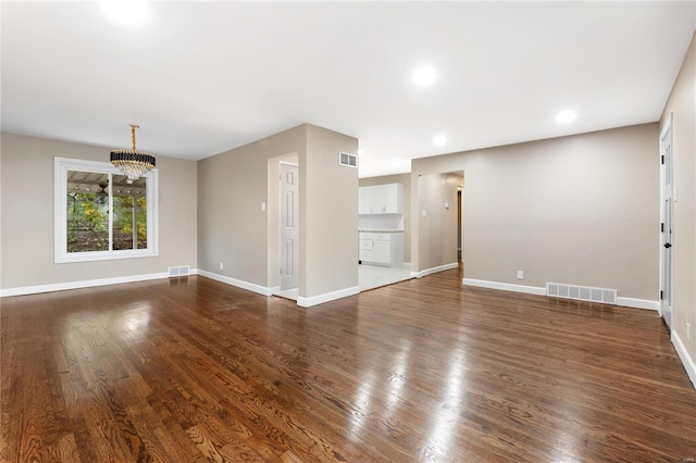 unfurnished living room featuring dark hardwood / wood-style flooring and a chandelier