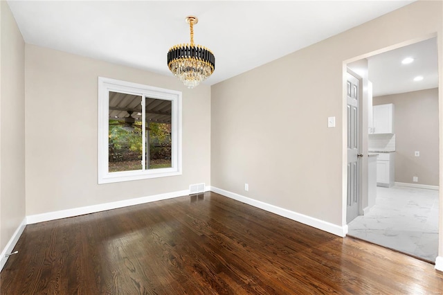 spare room with wood-type flooring and an inviting chandelier