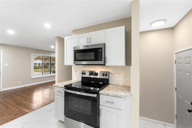 kitchen featuring light stone countertops, light hardwood / wood-style flooring, backsplash, white cabinets, and appliances with stainless steel finishes