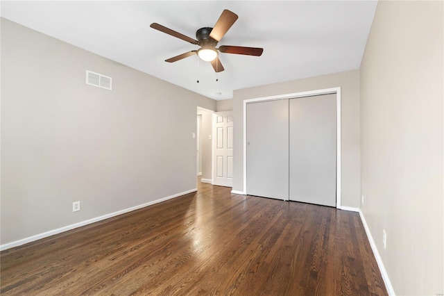 unfurnished bedroom with ceiling fan, dark wood-type flooring, and a closet