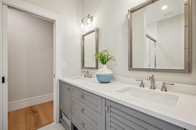 bathroom featuring vanity, a shower with shower door, and wood-type flooring