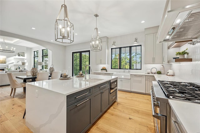 kitchen with sink, white cabinetry, light hardwood / wood-style floors, pendant lighting, and custom exhaust hood