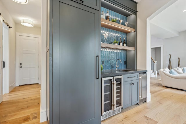 bar featuring wine cooler, sink, light hardwood / wood-style flooring, and gray cabinets