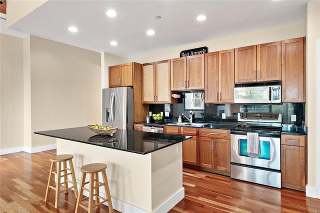 kitchen featuring a center island, stainless steel appliances, sink, light hardwood / wood-style flooring, and a kitchen bar