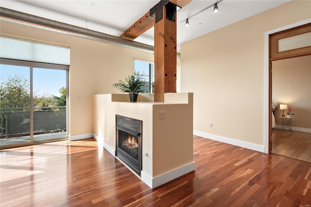 unfurnished living room featuring track lighting, hardwood / wood-style flooring, and a wealth of natural light