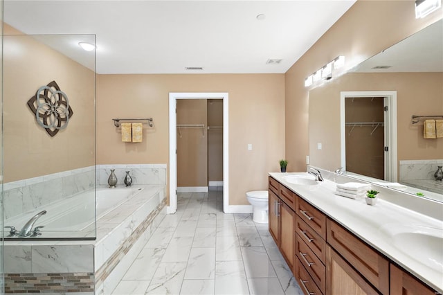 bathroom with toilet, vanity, and tiled bath