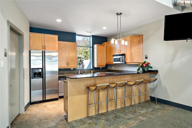 kitchen with stainless steel appliances, kitchen peninsula, decorative light fixtures, and a kitchen breakfast bar