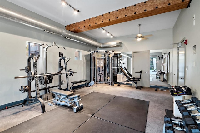 gym featuring ceiling fan, a towering ceiling, and rail lighting