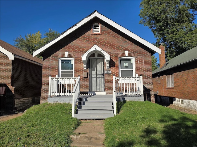 view of front of home with covered porch and a front lawn