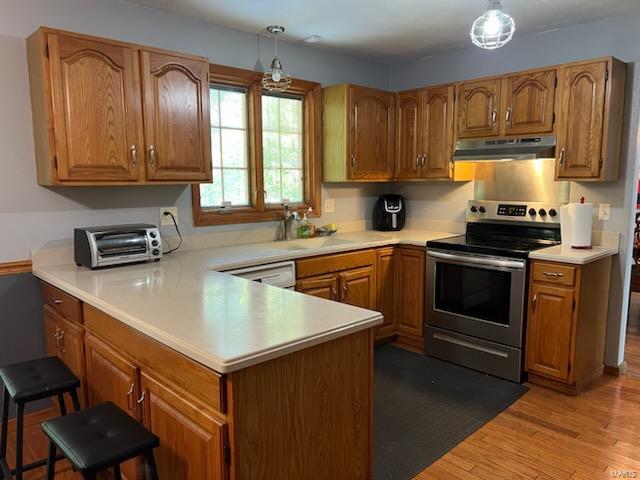 kitchen featuring kitchen peninsula, sink, pendant lighting, stainless steel electric range oven, and light hardwood / wood-style floors