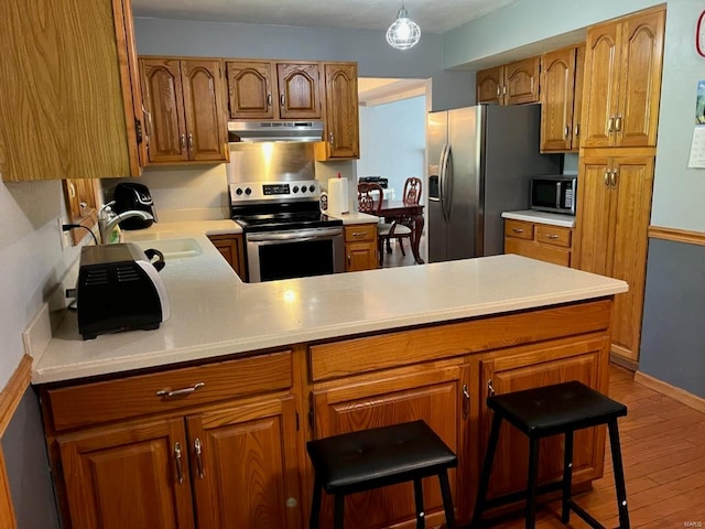 kitchen with kitchen peninsula, a breakfast bar, light hardwood / wood-style flooring, sink, and stainless steel appliances