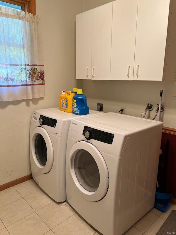 laundry area featuring cabinets, separate washer and dryer, and light tile patterned floors