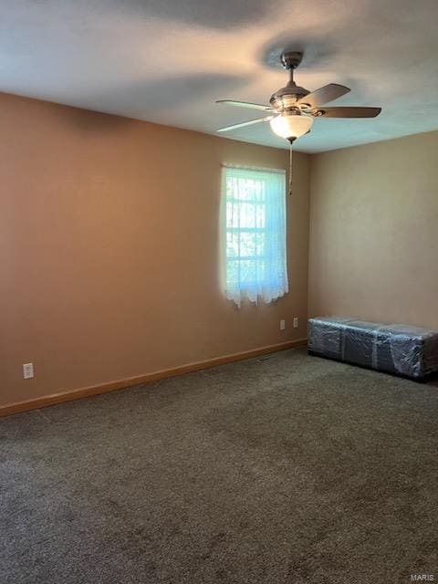 empty room featuring dark colored carpet and ceiling fan