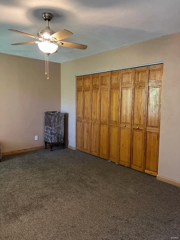 unfurnished bedroom featuring dark carpet, a closet, and ceiling fan