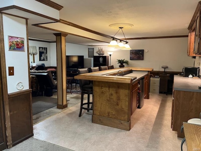 kitchen featuring a breakfast bar area, crown molding, decorative light fixtures, and a kitchen island