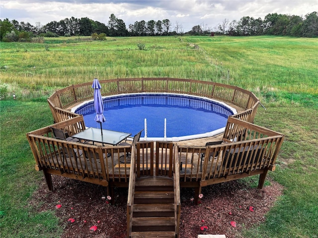 view of pool featuring a rural view, a lawn, and a wooden deck