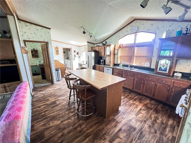 kitchen with lofted ceiling, appliances with stainless steel finishes, sink, and a textured ceiling