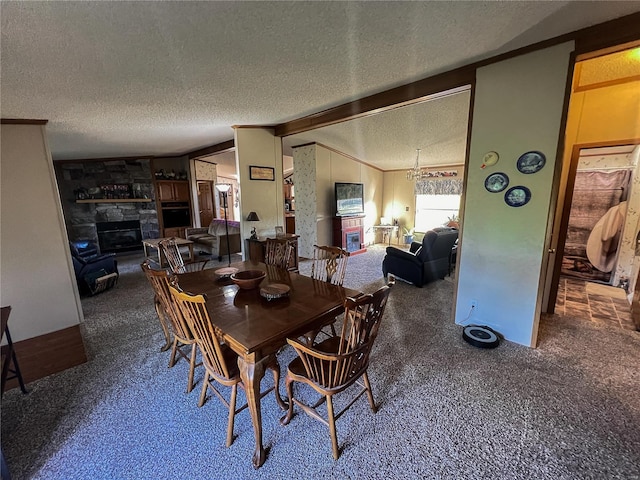 dining room with a textured ceiling, a fireplace, ornamental molding, vaulted ceiling with beams, and carpet flooring